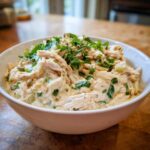 A close-up of a white bowl filled with creamy keto white chicken chili, topped generously with fresh cilantro.