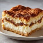 A rich, creamy slice of sopapilla cheesecake topped with cinnamon sugar.
