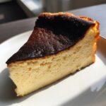 Close-up of a creamy slice of Basque cheesecake showing its signature dark, caramelized top.