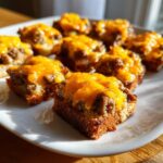 Close-up of several pieces of hanky panky recipe appetizers topped with melted orange cheddar cheese on toasted bread.