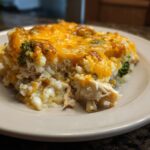 A close-up serving of cheesy chicken cauliflower rice casserole with visible shredded chicken and broccoli florets.