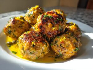 Close-up of browned chicken piccata meatballs served in a bright lemon-butter sauce with capers and parsley.