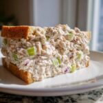A thick sandwich filled with creamy cottage cheese tuna salad, celery, and red onion, served on whole wheat bread.