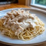 A plate of spaghetti topped with creamy sauce and shredded chicken from the crock pot angel chicken recipe.