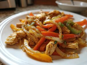 Close-up of seasoned chicken strips mixed with sautéed onions and colorful bell peppers, ready to eat crockpot chicken fajitas.