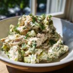 Close-up of creamy dill pickle chicken salad featuring chunks of chicken, pickles, and fresh dill.