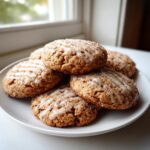 A stack of five soft, spiced apple cider cookies drizzled with white glaze and sprinkled with sugar.