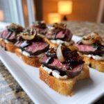 Close-up of several gourmet steak crostini appetizers topped with rare steak, creamy cheese, and balsamic onions.