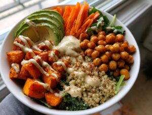 Close-up of a vibrant buddha bowl featuring roasted sweet potatoes, chickpeas, avocado, and quinoa.