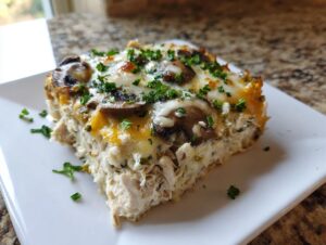 A hearty slice of keto garlic mushroom chicken casserole topped with melted cheese and fresh parsley.