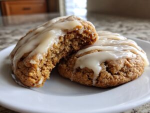 Close-up of two soft maple brown sugar cookies drizzled with a light glaze, one cookie broken open.