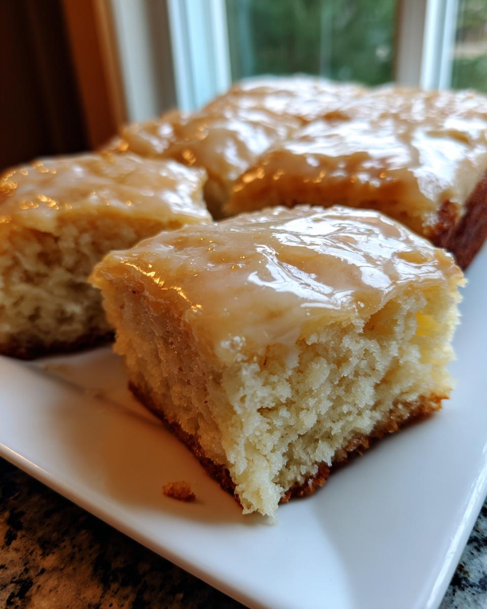 A close-up of a square piece of fluffy maple donut bars topped with a thick, shiny maple glaze.