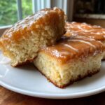 Close-up of two square maple donut bars stacked on a white plate, showing the fluffy interior and thick maple glaze.