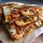 Close-up of stacked, grilled shrimp quesadilla wedges showing melted cheese and plump shrimp.