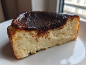 A close-up slice of creamy Basque burnt cheesecake showing its signature dark, caramelized top.