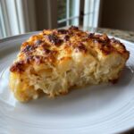 A thick slice of creamy potatoes au gratin with a perfectly browned, cheesy crust served on a white plate.