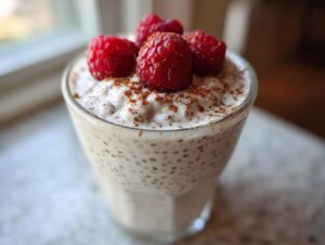 Close-up of creamy chia seed pudding topped with fresh raspberries and cinnamon.
