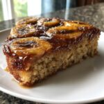 A close-up of a moist slice of banana foster upside down cake showing caramelized banana topping.
