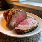 A thick slice of perfectly cooked beef standing rib roast showing a medium-rare pink center and herb crust.