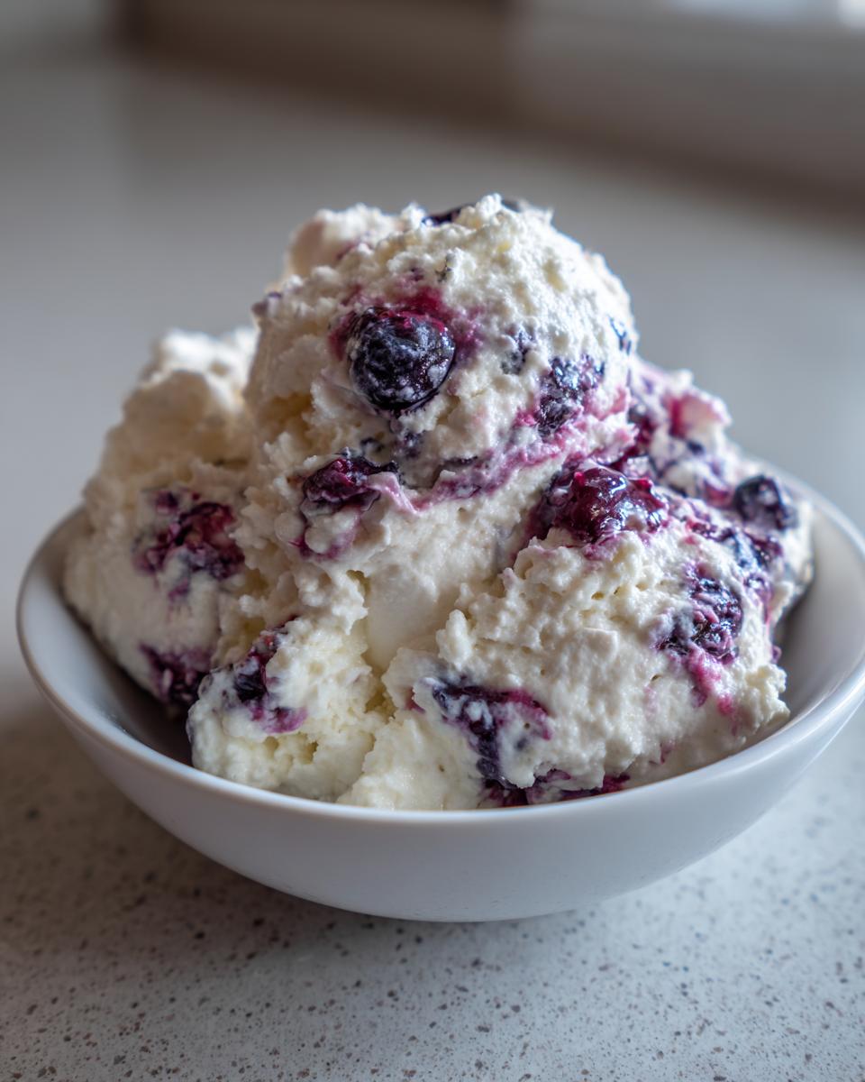 Close-up of fluffy white blueberry fluff salad mixed with swirls of purple blueberry sauce in a small white bowl.