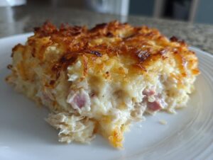 A close-up of a serving of creamy chicken cordon bleu casserole showing shredded chicken and ham pieces.