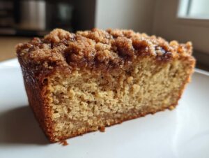 Close-up of a moist slice of coffee cake banana bread featuring a thick, rich cinnamon streusel topping.