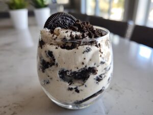 A single serving of creamy cookies and cream mousse layered with crushed chocolate sandwich cookies and topped with a whole cookie.