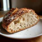 A close-up of a slice showing the open, airy crumb of a country loaf with sourdough discard.