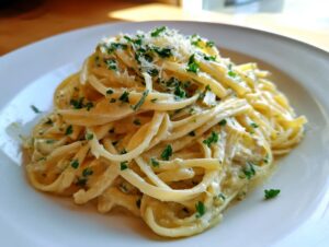 A close-up of creamy Artichoke pasta twirled high on a white plate, garnished with grated cheese and fresh parsley.