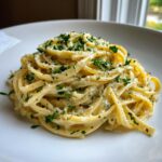 Close-up of a swirl of creamy Artichoke pasta topped with fresh chopped parsley and grated Parmesan cheese.