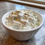 A close-up of thick, creamy homemade tartar sauce packed into a small white bowl.