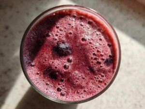 Overhead view of a vibrant, deep red healthy fruit smoothie with kefir, showing a foamy top and whole berries.