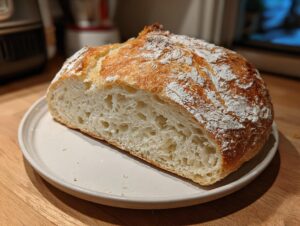 Cross-section view showing the open, airy crumb structure of a homemade ciabatta loaf dusted with flour.