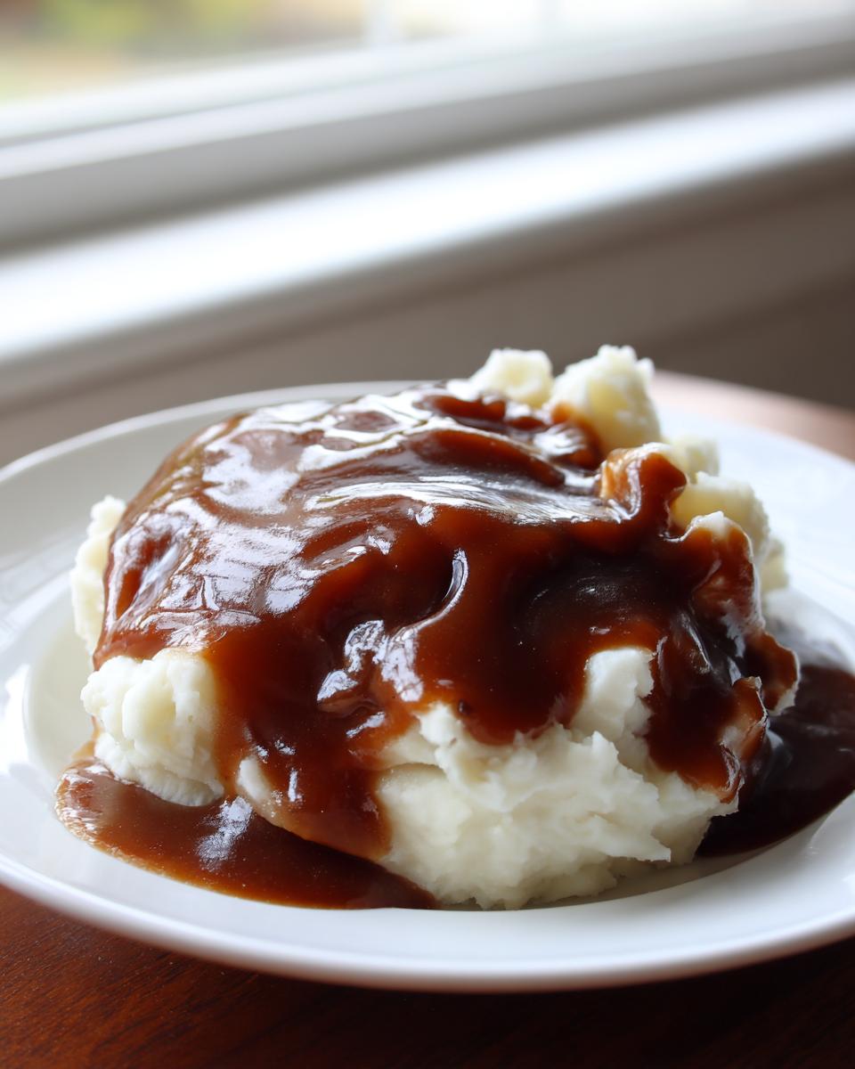 A generous serving of mashed potatoes smothered in rich, brown homemade KFC gravy copycat sauce.