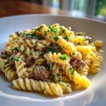 A close-up of a serving of 1 pot creamy beef and garlic pasta using fusilli noodles, topped with fresh parsley.