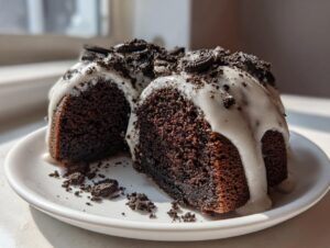 Two slices of dark chocolate Oreo bundt cake covered in white vanilla glaze and crushed Oreos.