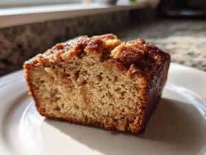Close-up of a moist slice of snickerdoodle banana bread showing the crumb texture and caramelized cinnamon sugar top.