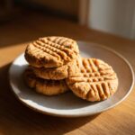 A stack of freshly baked 3 ingredient peanut butter cookies with classic fork marks, resting on a speckled plate.