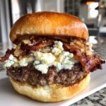 A juicy Bacon blue cheese burger stacked high with a thick patty, melted cheese, crispy bacon, and blue cheese crumbles on a brioche bun.
