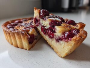 Cross-section view of a rich Cherry almond tart slice showing the buttery crust and creamy filling topped with glossy cherries.