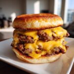 A delicious double patty Classic smash burger dripping with melted American cheese on toasted buns, served on a white plate.