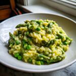 Close-up of creamy Asparagus risotto mixed with bright green peas, served in a white bowl.