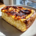 Close-up of a thick slice of Creme brulee french toast with a caramelized, dark brown top.