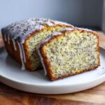 Two slices of moist Earl Grey lavender loaf cake, dotted with poppy seeds and topped with white glaze and lavender sprinkles.