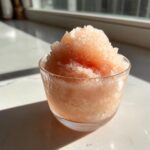 A close-up of a glass filled with icy, slushy Frozen rosé (frosé) sitting on a sunny countertop.