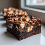 Close-up of a fudgy Rocky Road Brownie bite topped with toasted marshmallows, nuts, and chocolate chips.