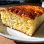 Close-up of a thick, golden slice of fluffy sheet pancakes served on a white plate.