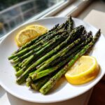 A bright serving of perfectly grilled asparagus with lemon wedges on a white plate.