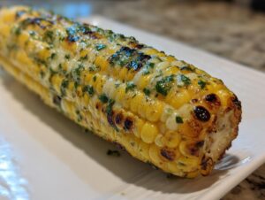 Close-up of perfectly grilled corn with herb butter melting over the kernels.