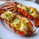Close-up of two halves of grilled lobster tail, split open and basted with melted garlic butter and parsley.